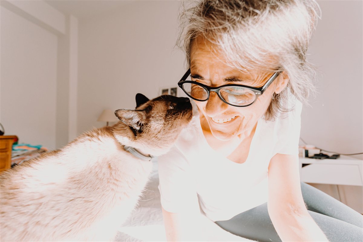 Mujer sonriendo junto a su gato, vínculo de confianza